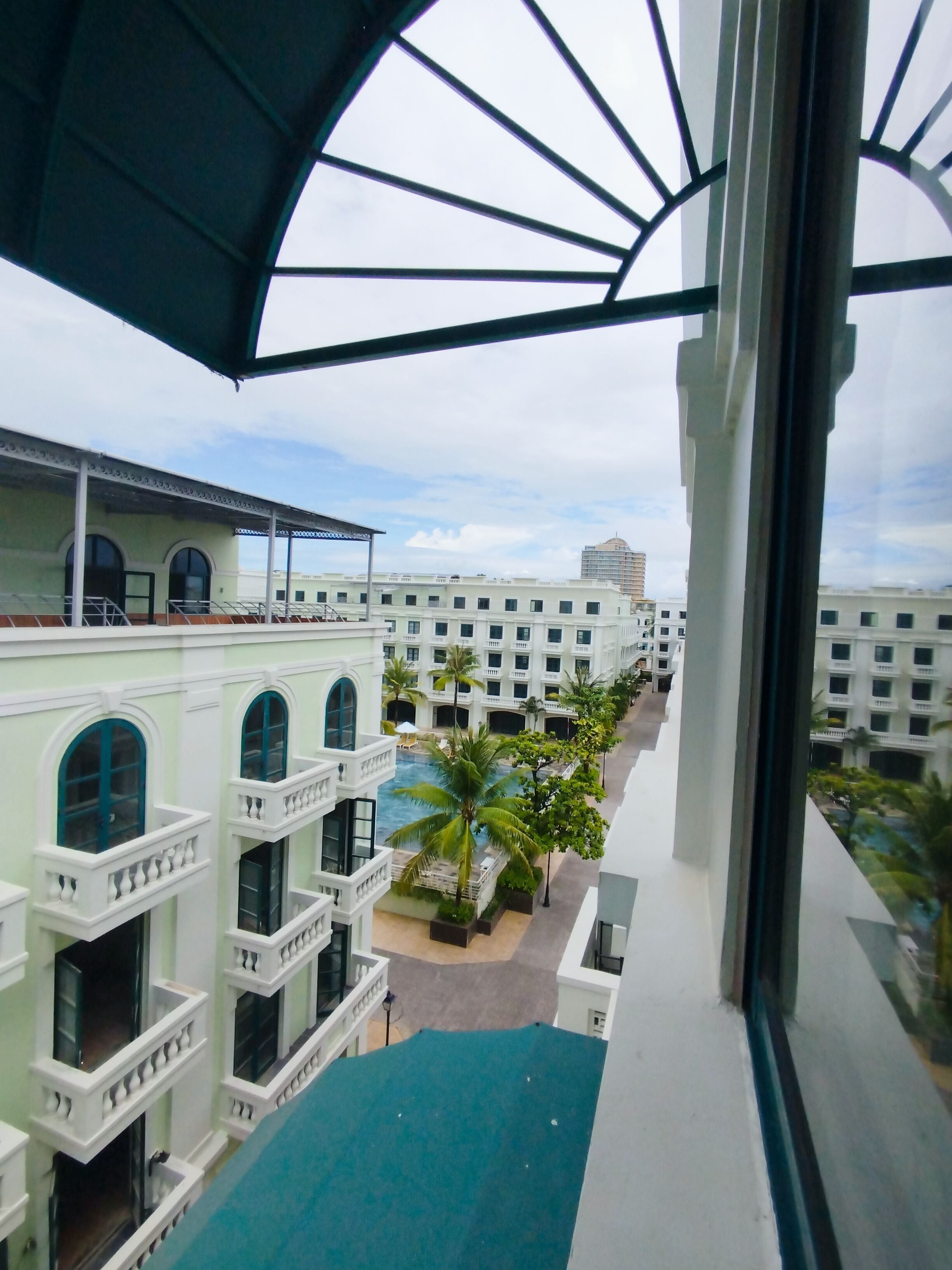 Un hotel con varios balcones, piscina y vistas de edificios circundantes.