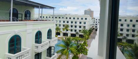 Un hotel con varios balcones, piscina y vistas de edificios circundantes.