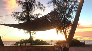 A beach bar with a bamboo fence, bar stools, and a sign reading "BEACH BAR". - Kalia Phu Quoc Hotel 2 (Phu Quoc)