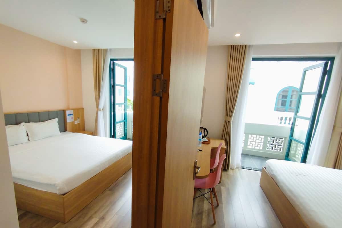 Una camera d'albergo con due letti, una scrivania con una sedia e un balcone con vista.
