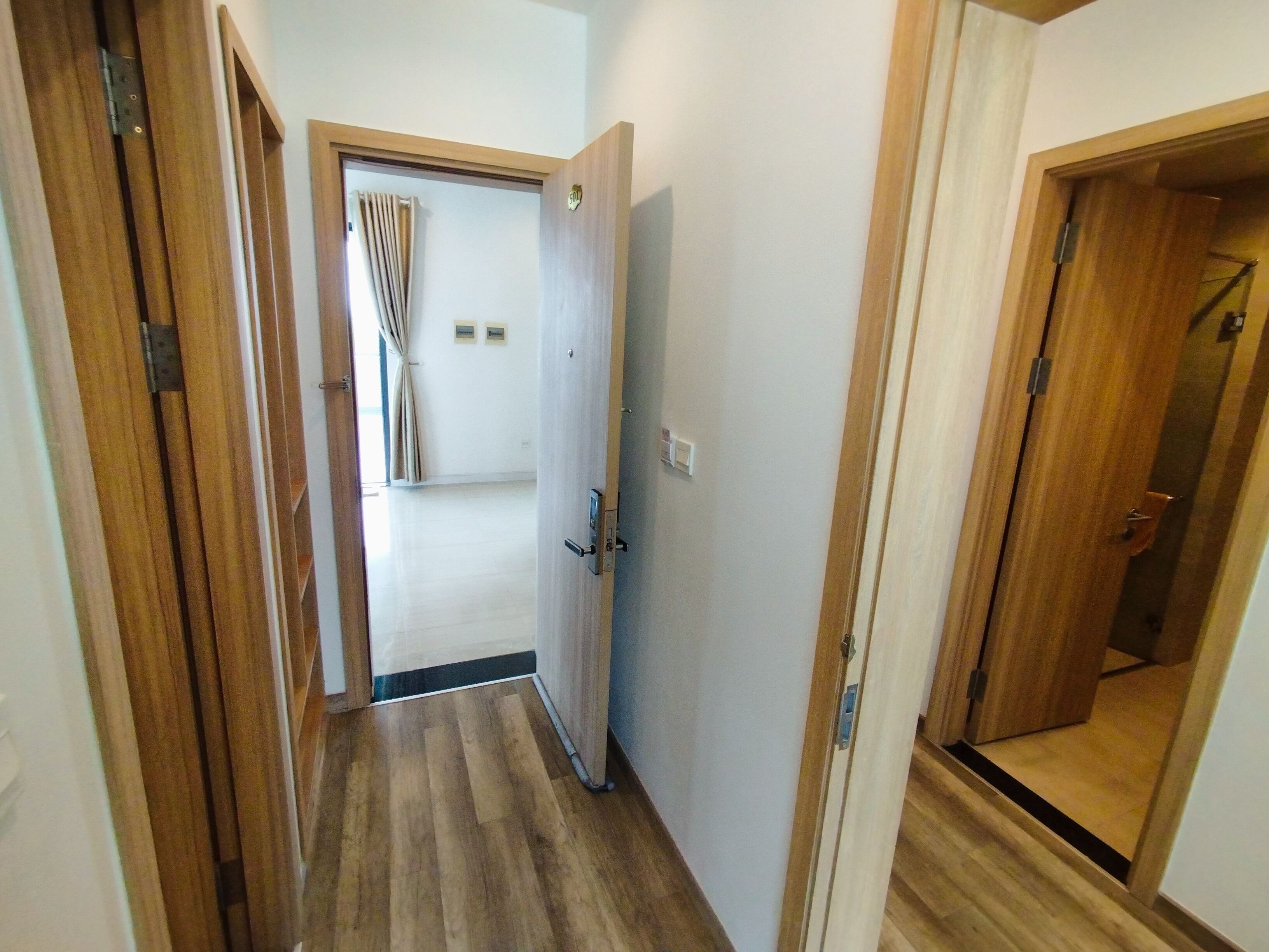 Un pasillo con suelo de madera y puertas que dan a habitaciones.