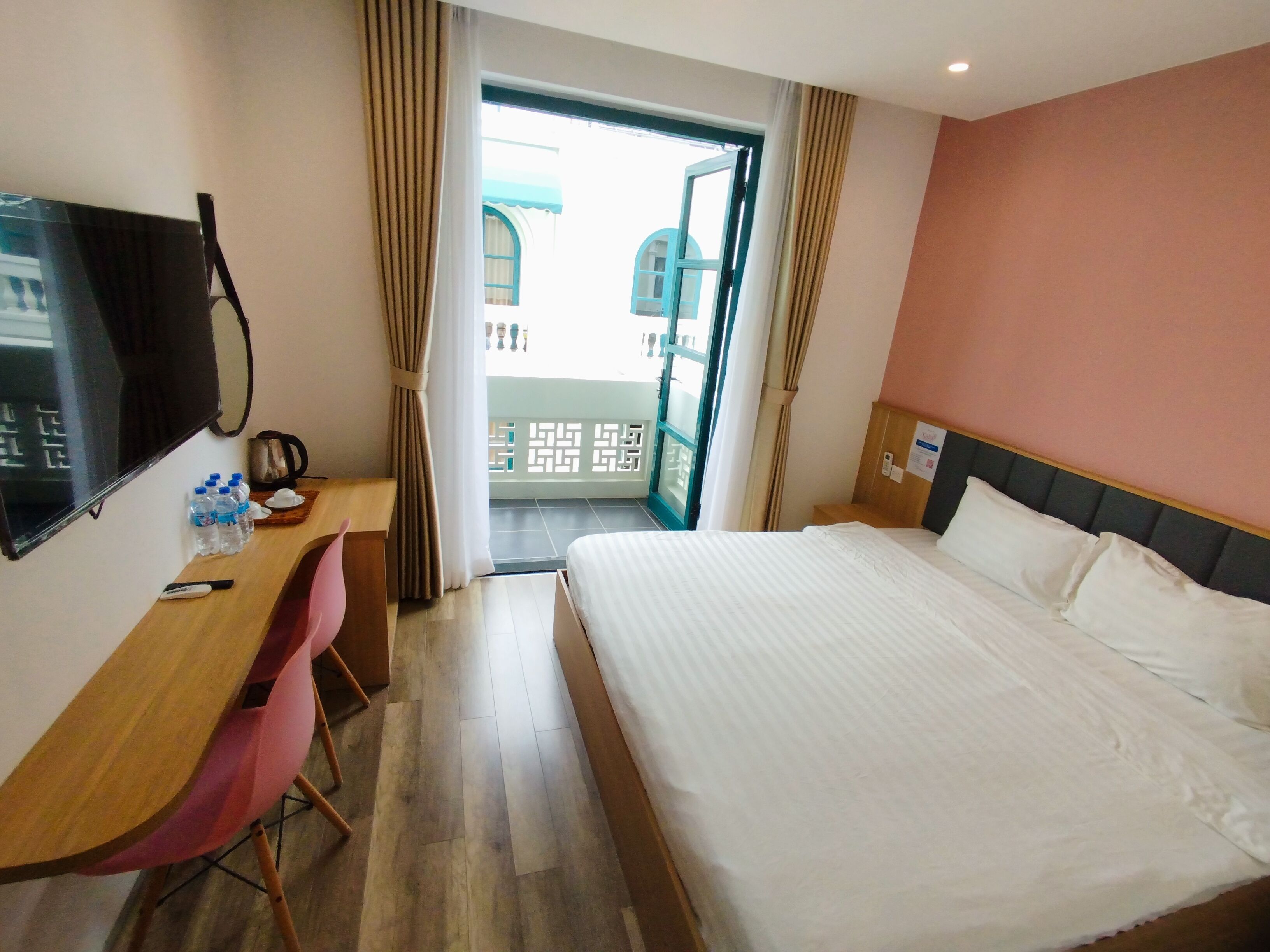A hotel room with a bed, a desk, a chair, a television, and a window with curtains.