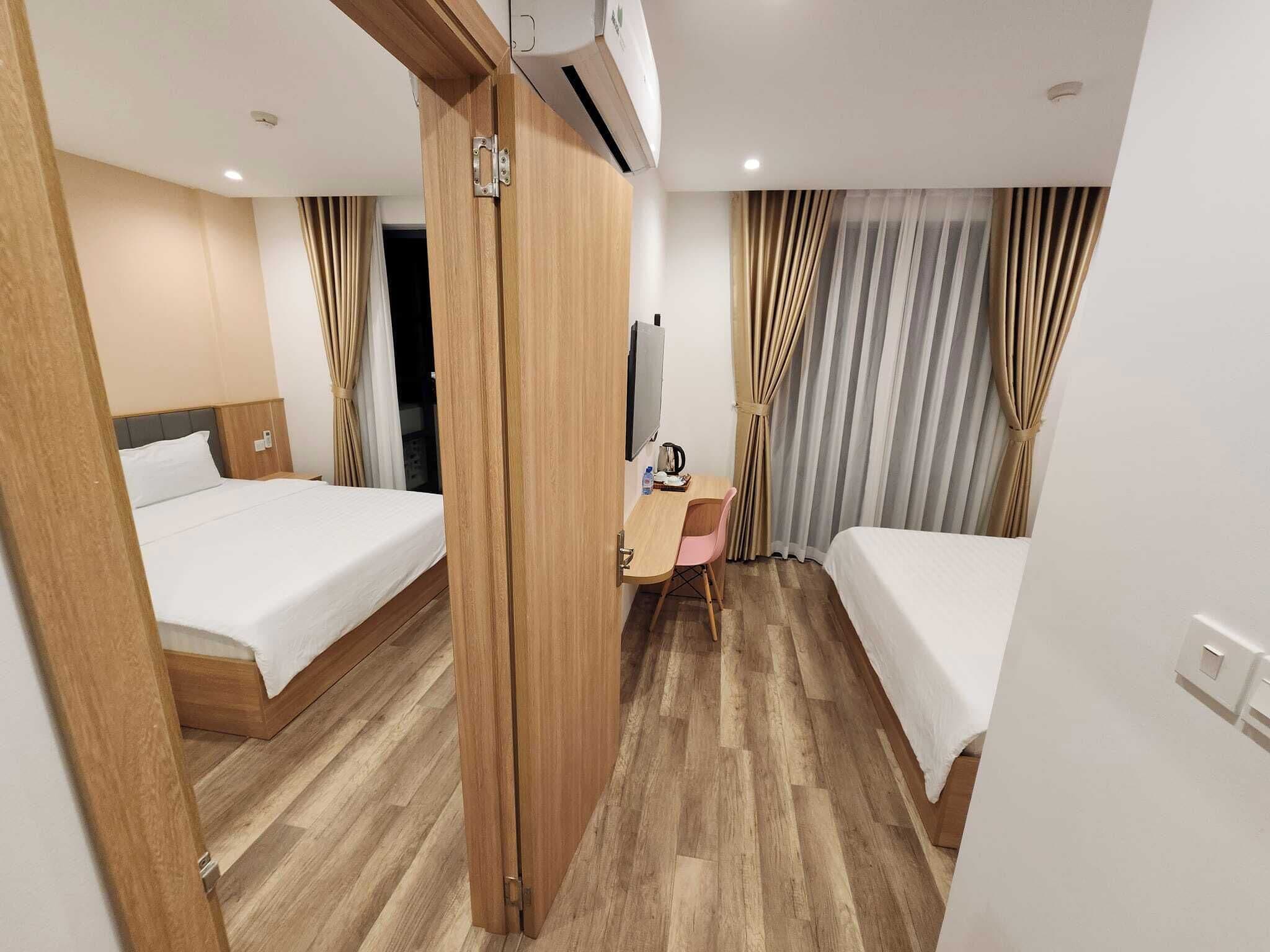 A hotel room with two beds, a desk, a chair, and a TV.