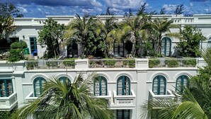 A multi-story building with arched windows and balconies, surrounded by lush greenery. - Kalia Phu Quoc Hotel 2 (Phu Quoc)