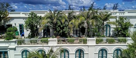 A multi-story building with arched windows and balconies, surrounded by lush greenery.