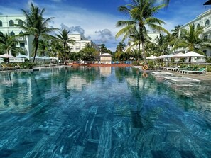 A large swimming pool with clear blue water, surrounded by palm trees and sun loungers. - Kalia Phu Quoc Hotel 2 (Phu Quoc)