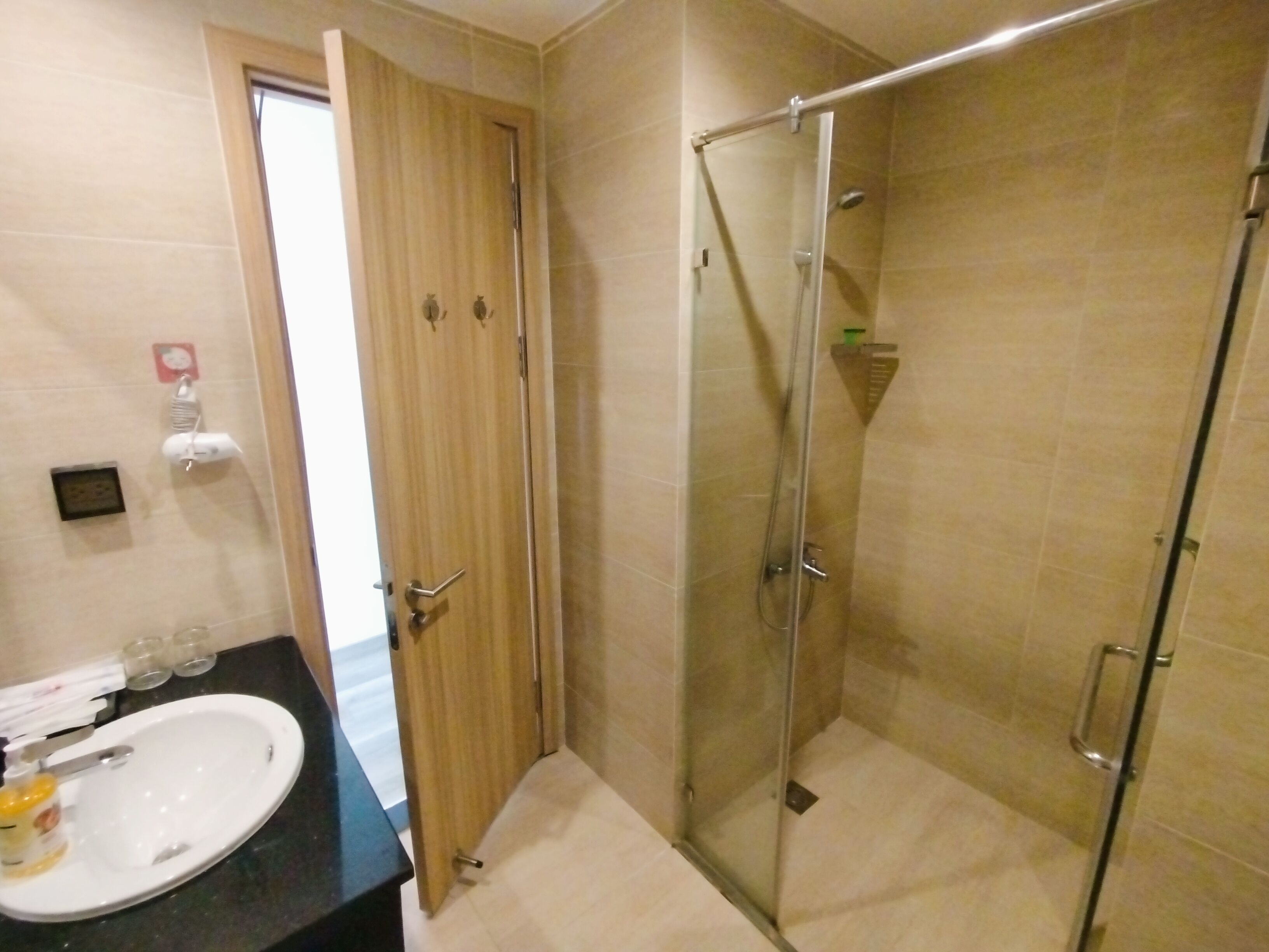 Une salle de bain avec une douche à parois de verre, un lavabo et une porte en bois.
