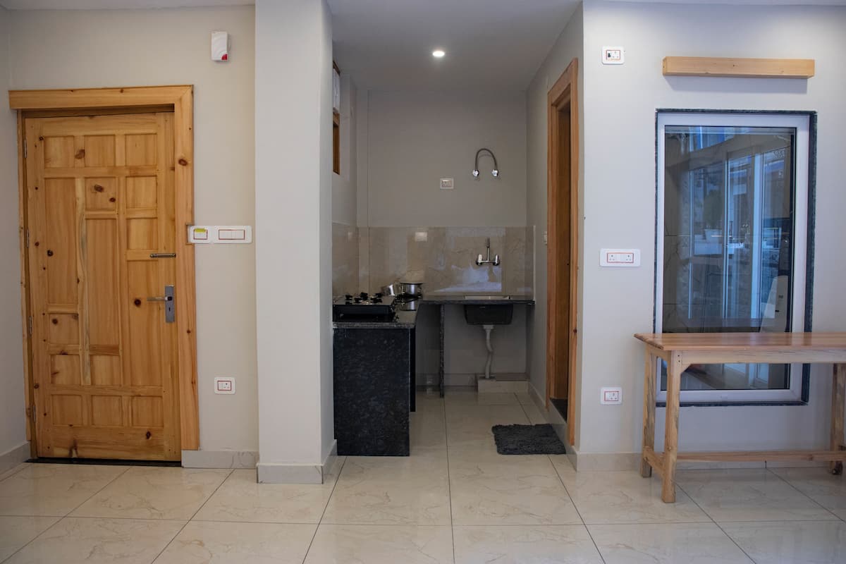 A compact kitchen with a wooden door, a small sink, and a window.