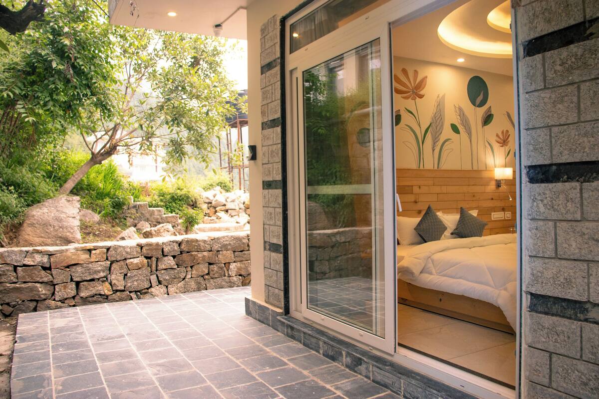 A bedroom with a sliding glass door, a stone wall, and a bed with pillows.