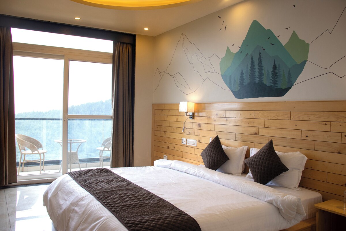 A hotel room with a large bed, wooden headboard, and a view of the sea through a large window.