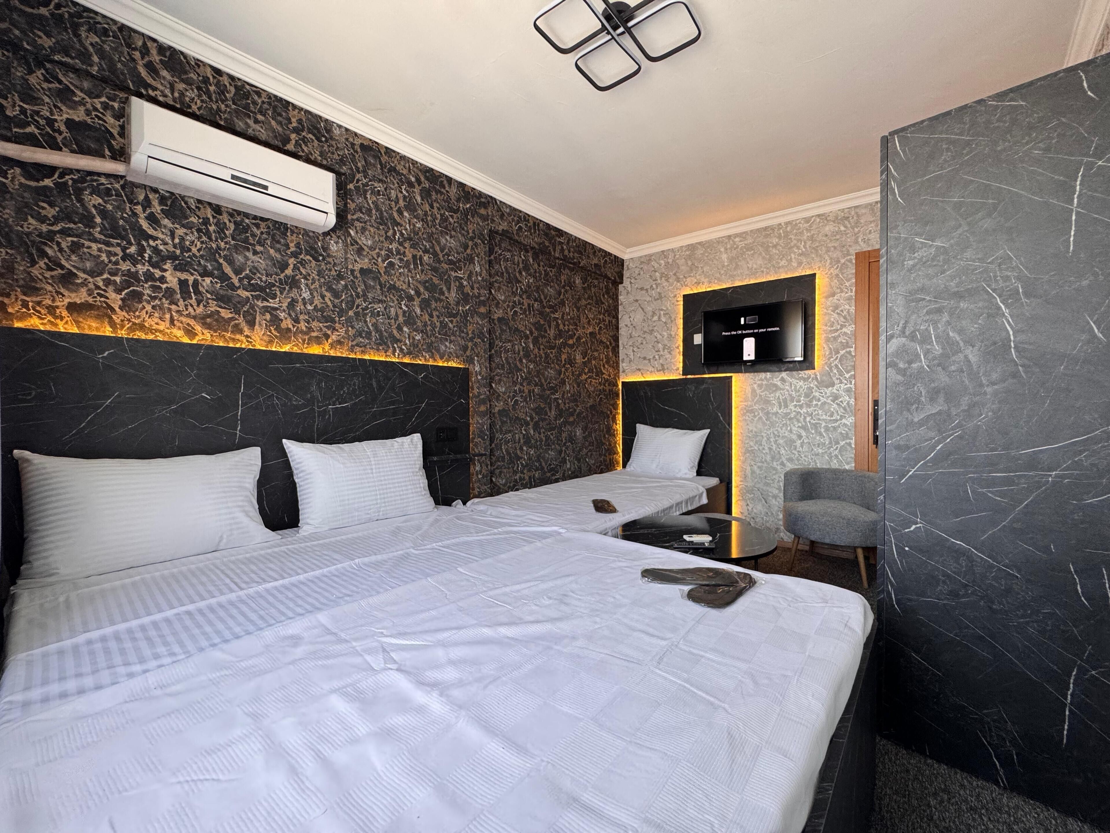 Ein Hotelzimmer mit zwei Betten, einem flachbildfernseher an der Wand und einer Klimaanlage über den Betten.