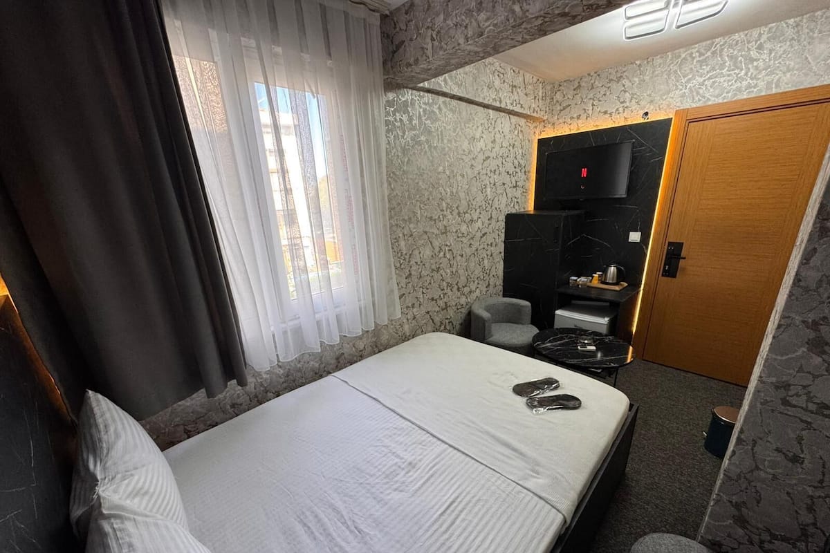 Habitación de hotel con cama, escritorio, silla, televisor y armario.