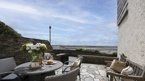 Een terras met rieten meubels, een ronde tafel en een potplant.