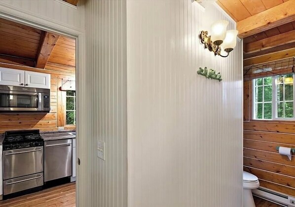 A kitchen with stainless steel appliances, a wooden ceiling, and a window with a view of greenery.
