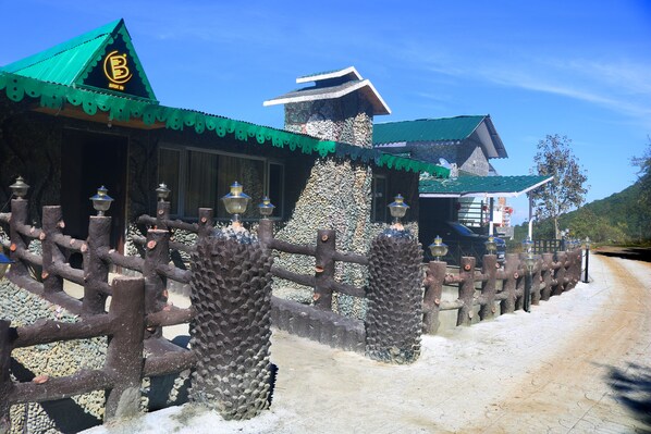 Un edificio tradicional con techo verde y pared de piedra.