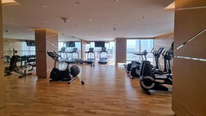 Une salle de sport spacieuse équipée de divers appareils de cardio, de matériel de musculation et d’un grand miroir qui reflète l’ensemble de la pièce.