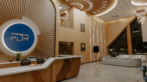 A modern reception area with a circular logo, wooden paneling, and a seating area with a large window. - Floating deck resort  (Bhuj)