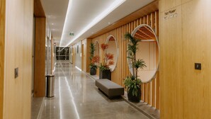 A modern hotel corridor with wooden paneling, a bench, and potted plants. - Floating deck resort  (Bhuj)