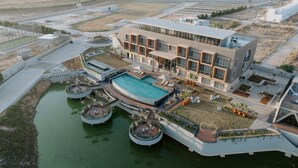 A modern hotel with a central swimming pool, multiple balconies, and a landscaped garden area. - Floating deck resort  (Bhuj)