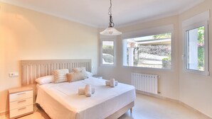 A bedroom with a bed, bedside tables, a radiator, and large windows. - Spectacular villa with private pool and sea views in Denia (Denia)