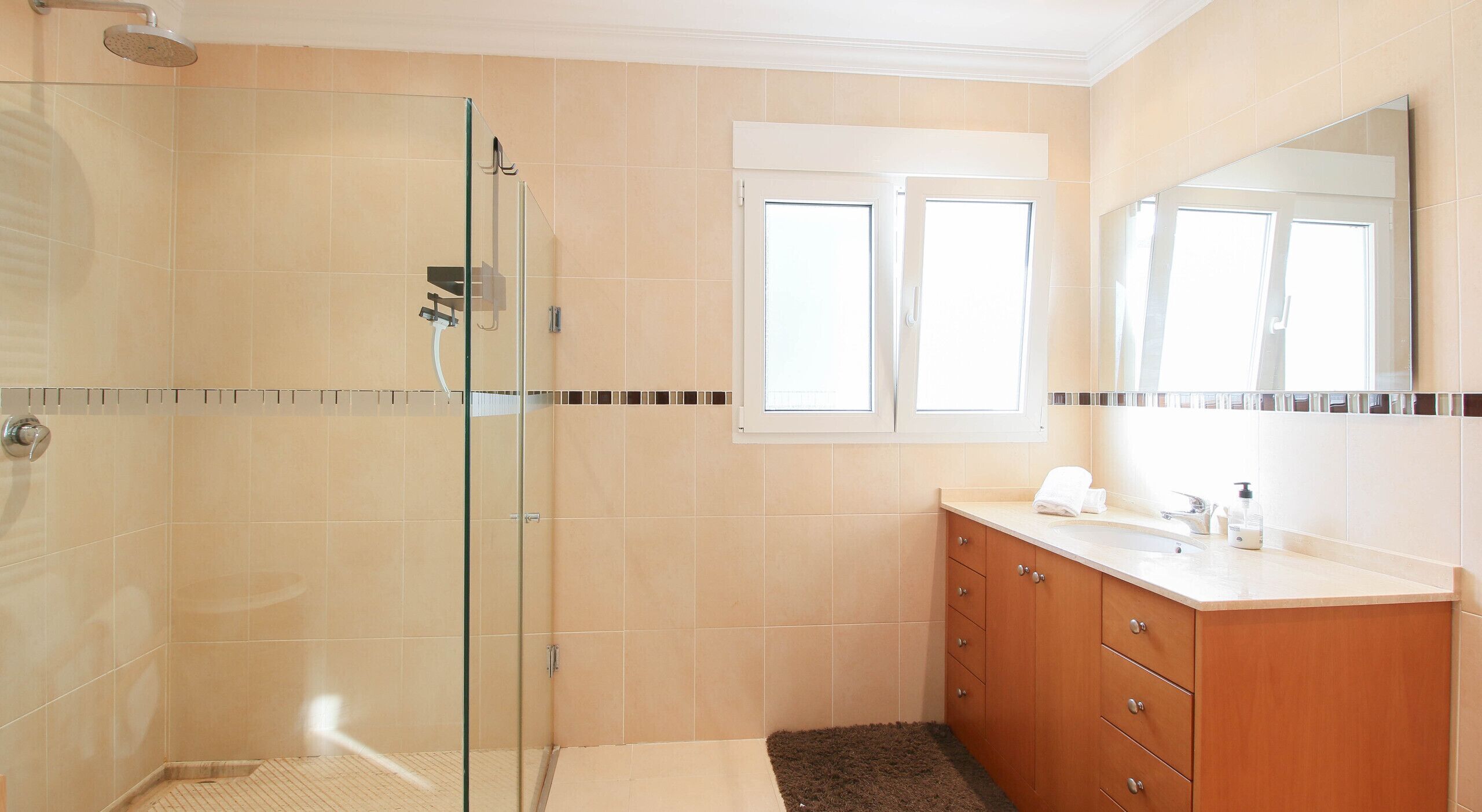 Een moderne badkamer met een douchecabine van glas, een wastafelmeubel met een wastafel en een spiegel erboven.