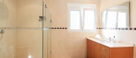 Een moderne badkamer met een douchecabine van glas, een wastafelmeubel met een wastafel en een spiegel erboven.
