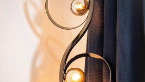 Eine wandmontierte Leuchte mit spiralförmigem Design und drei kugelförmigen Glühbirnen.