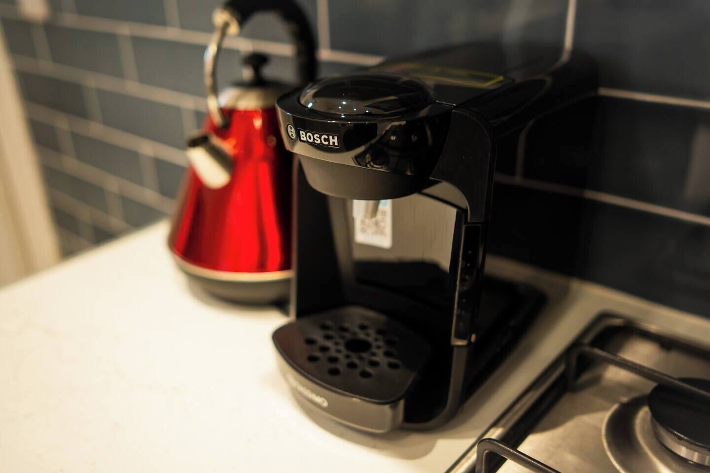 A coffee maker with a digital display and a red kettle on a kitchen counter.