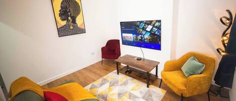 Un soggiorno con divano, poltrona e TV che mostra contenuti Netflix.