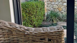 Una silla de mimbre en un patio con un muro de piedra y un edificio al fondo.