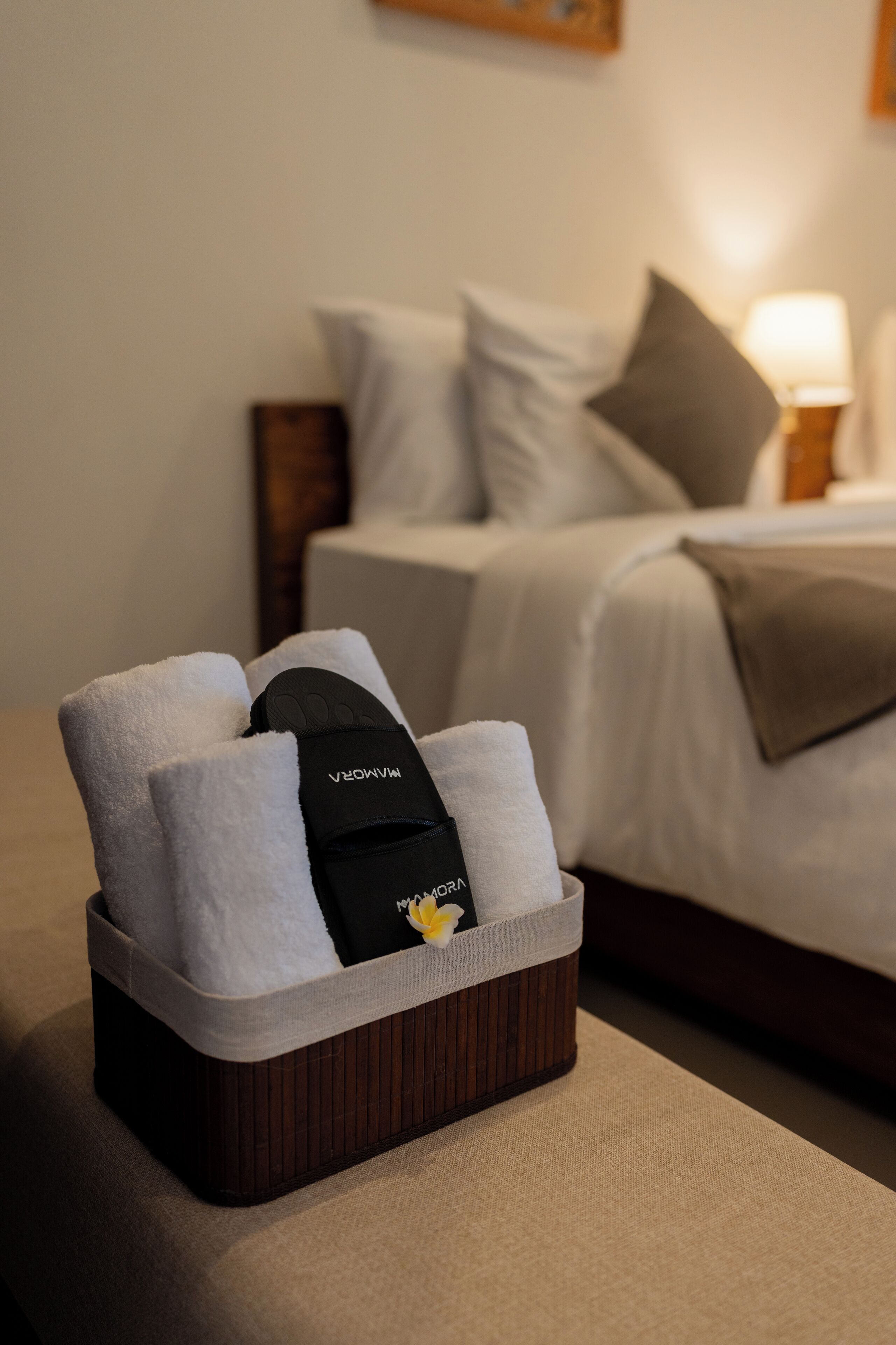 Un plateau bien rangé, avec des serviettes et une casquette noire, est posé sur un lit dans une chambre d’hôtel.