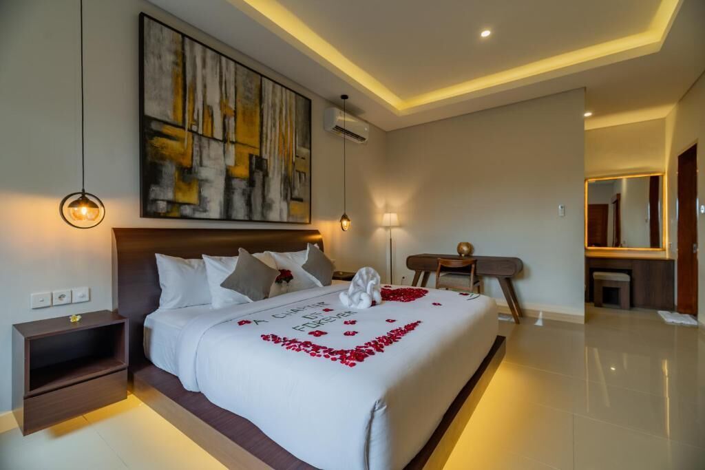 A modern hotel room with a large bed, a desk, and a large abstract painting on the wall.