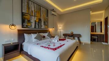 A modern hotel room with a large bed, a desk, and a large abstract painting on the wall.