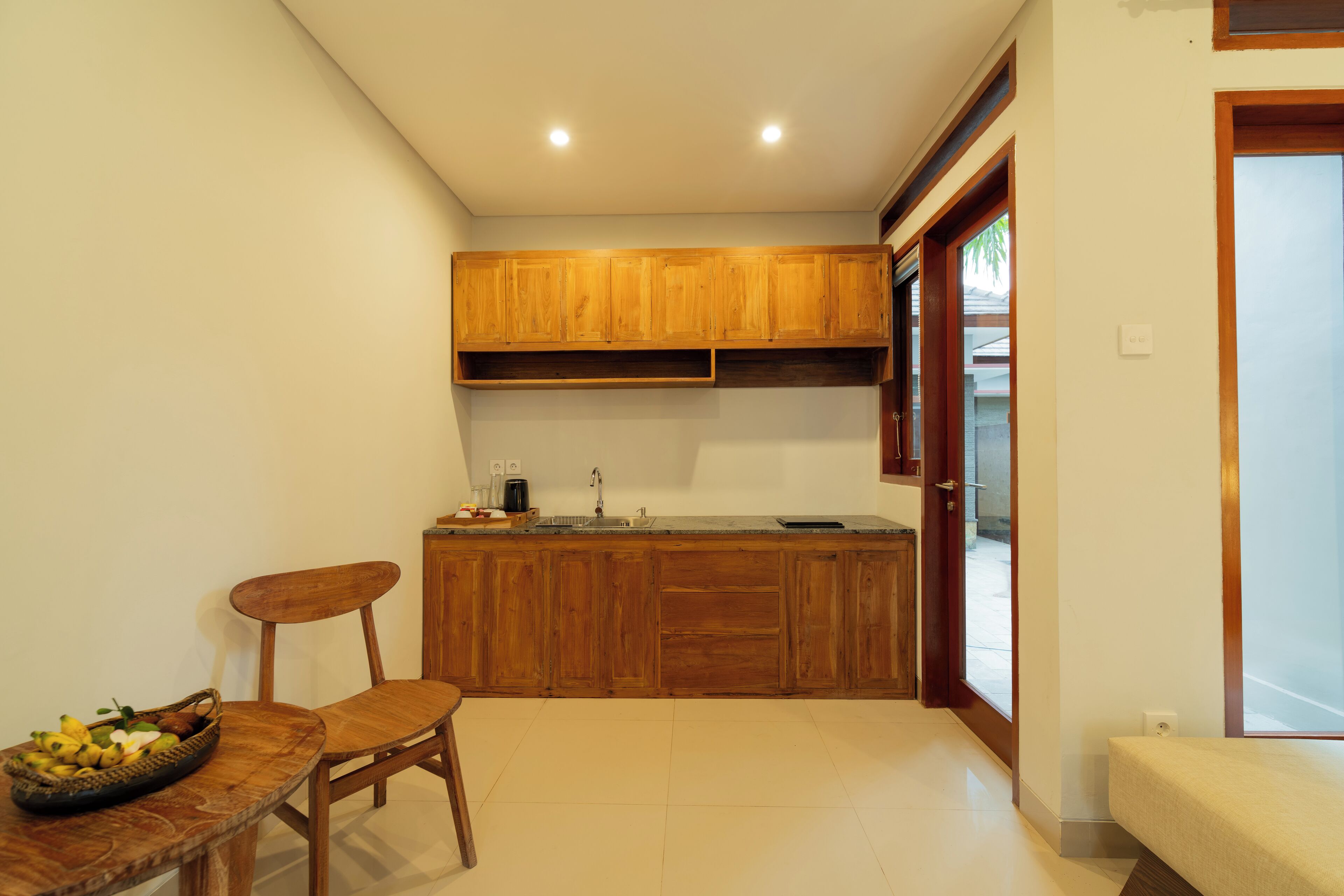 Une cuisine compacte avec des meubles de rangement en bois, un évier et un coin repas comprenant une chaise et une table.