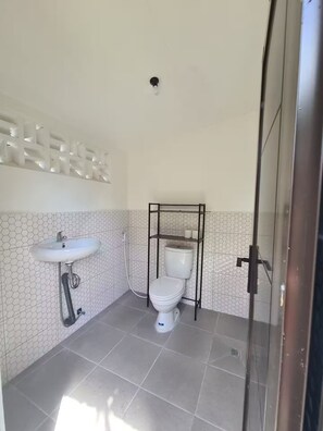 A bathroom with a white sink, toilet, and shower area.