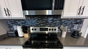 A kitchen with a stainless steel stove, oven, and microwave. There are cabinets with handles, a countertop with a toaster, and a blender. - Tigers Geaux Time Getaway in Baton Rouge -  SD5631 (Baton Rouge)