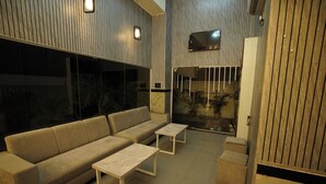 Un salon moderne avec un canapé, deux tables basses et un téléviseur fixé au mur.