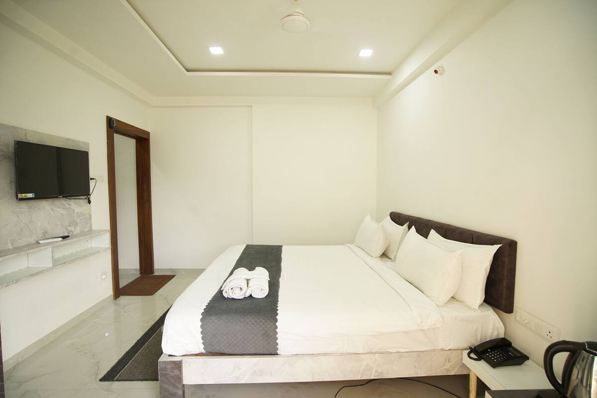 A hotel room with a bed, a bedside table, a telephone, and a television mounted on the wall.