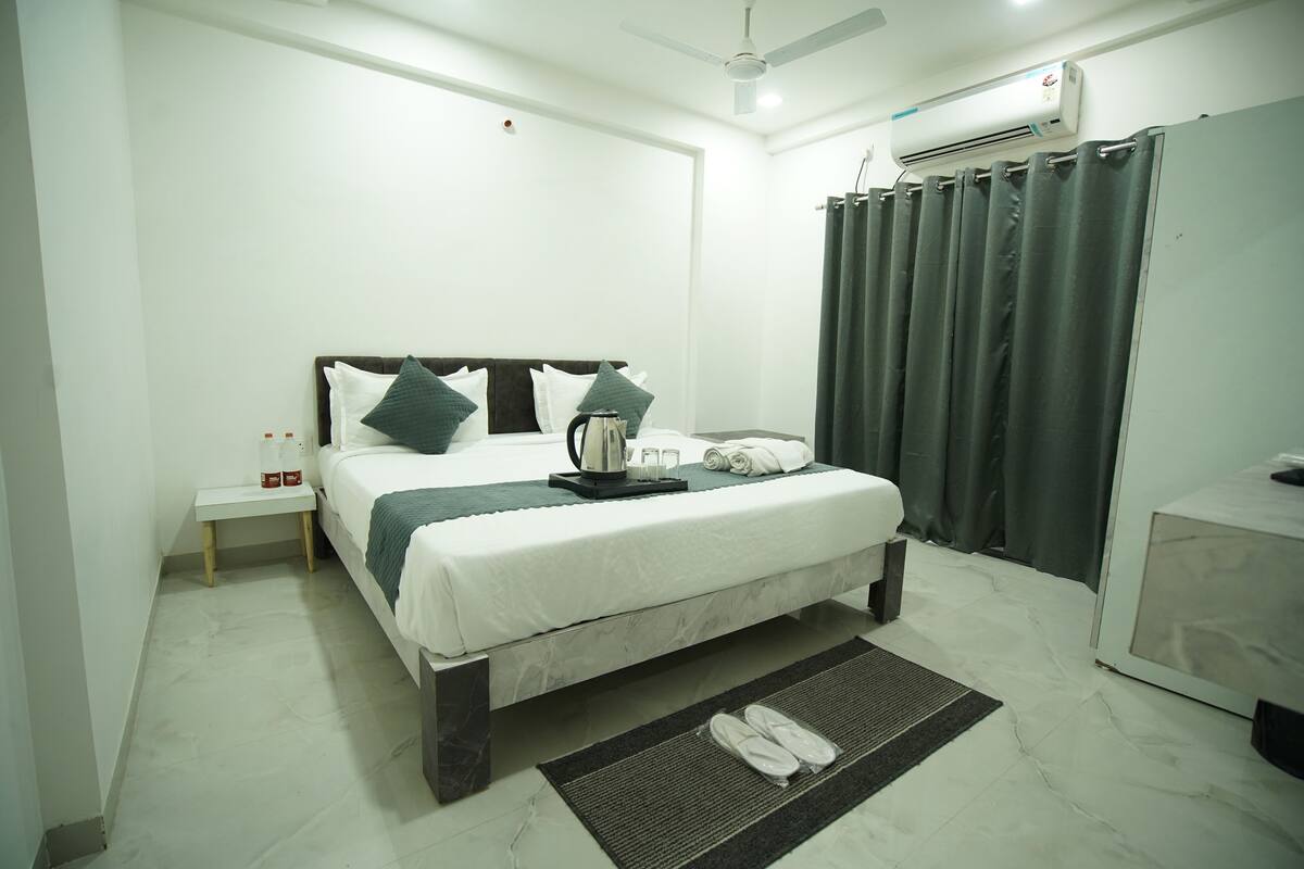 A hotel room with a bed, a nightstand, a coffee maker, and a bathroom with a shower curtain.