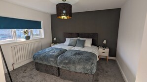 A bedroom with a bed, bedside tables, a window with a view, and a radiator. - Modern Gilliver house Rural retreat sleeps 7 (Newbold Verdon)