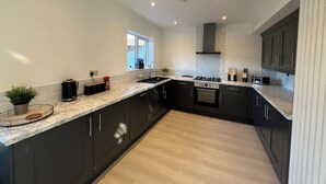 A modern kitchen with dark cabinets, a marble countertop, and a central island. - Modern Gilliver house Rural retreat sleeps 7 (Newbold Verdon)