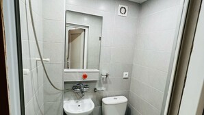 A compact bathroom with a pedestal sink, a toilet, and a shower.