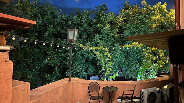 An outdoor patio with a string of lights, a lantern, and a hot air balloon in the background.