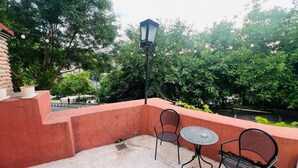An outdoor patio with a round table and two chairs, a street lamp, and a brick wall.