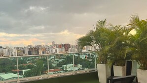 Una terraza en la azotea con dos sillones de relax, una planta en maceta y vistas a un paisaje urbano.