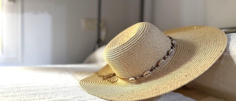 A straw hat with a beaded band, placed on a textured fabric surface.