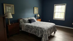 Une chambre à coucher avec un lit, deux tables de chevet, une commode et une fenêtre.