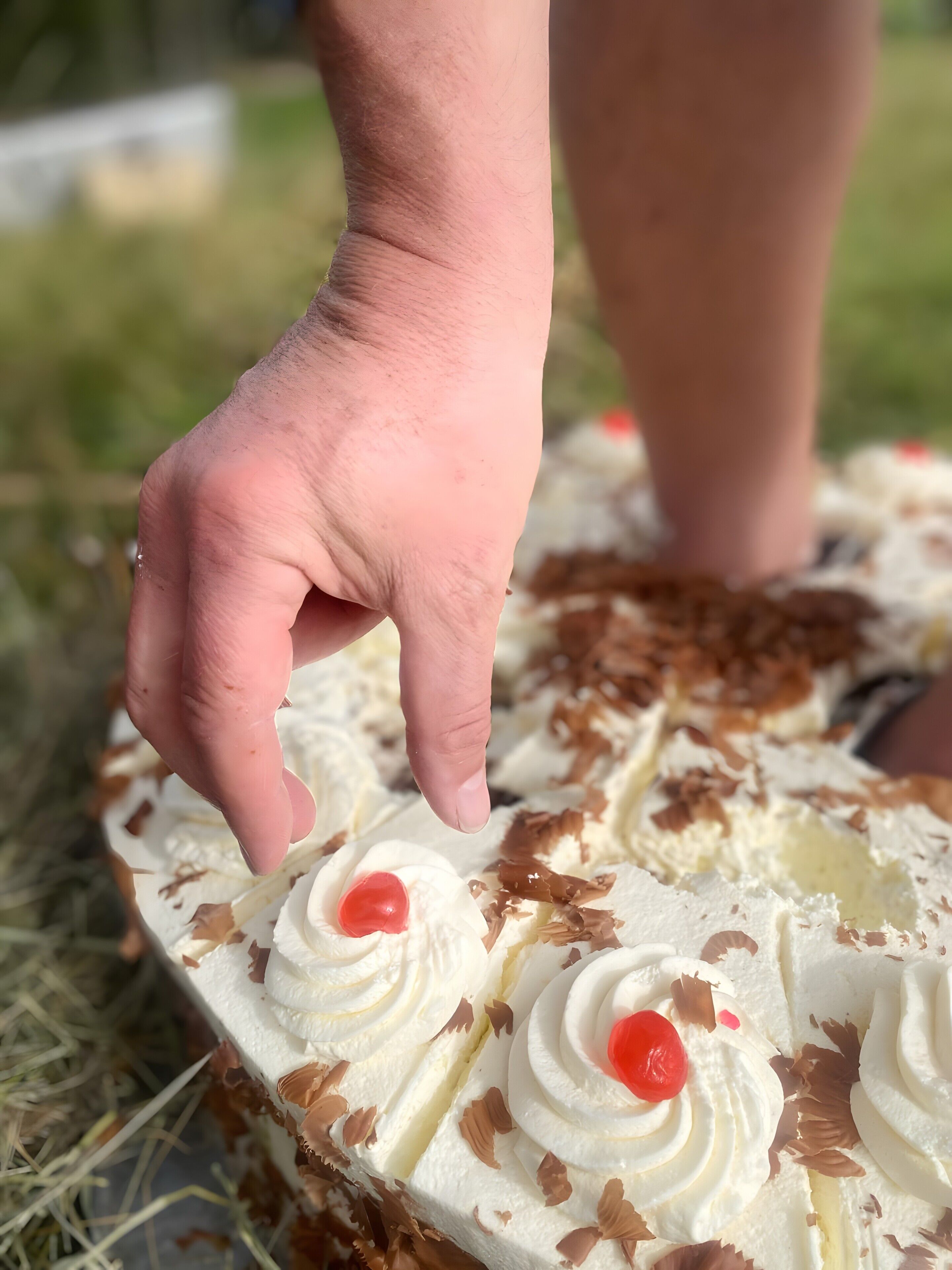 Une main touchant un dessert garni de crème fouettée et de copeaux de chocolat.