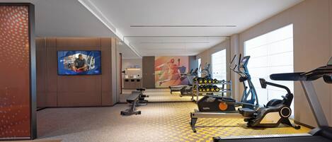 A modern gym with treadmills, elliptical machines, and weight benches.