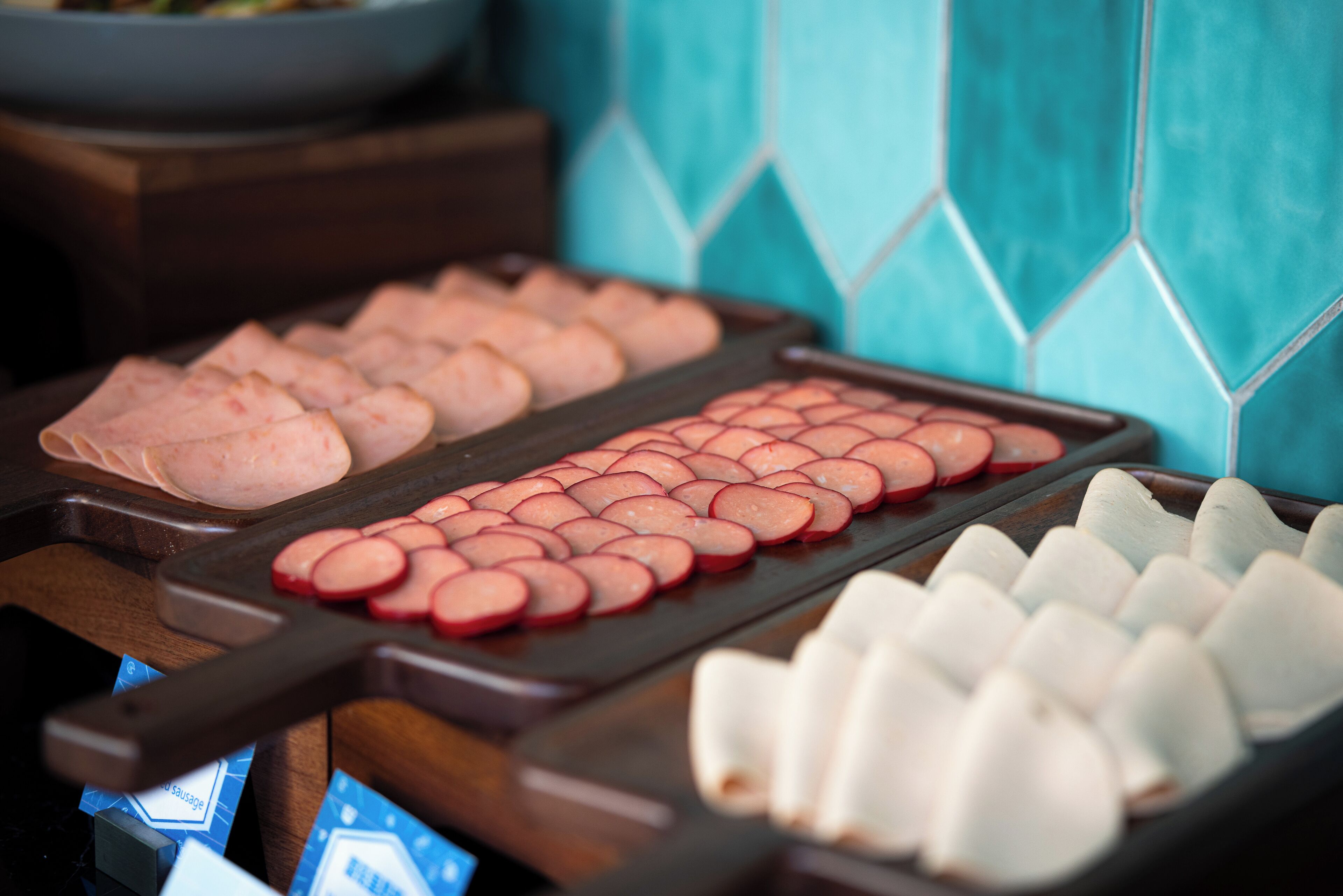Un bufé con diversos alimentos, incluyendo carnes en rodajas y verduras.